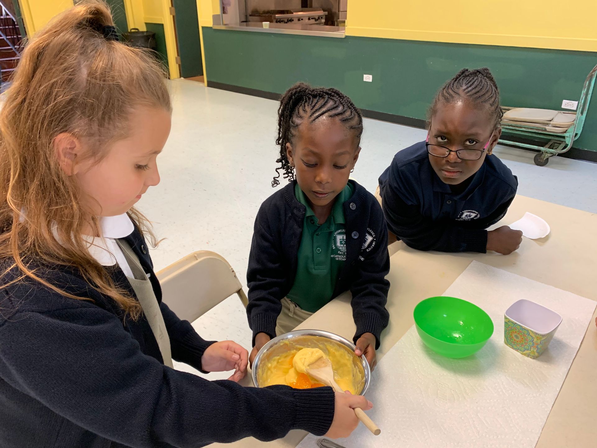 Students taking turns stirring batter at a cafeteria table