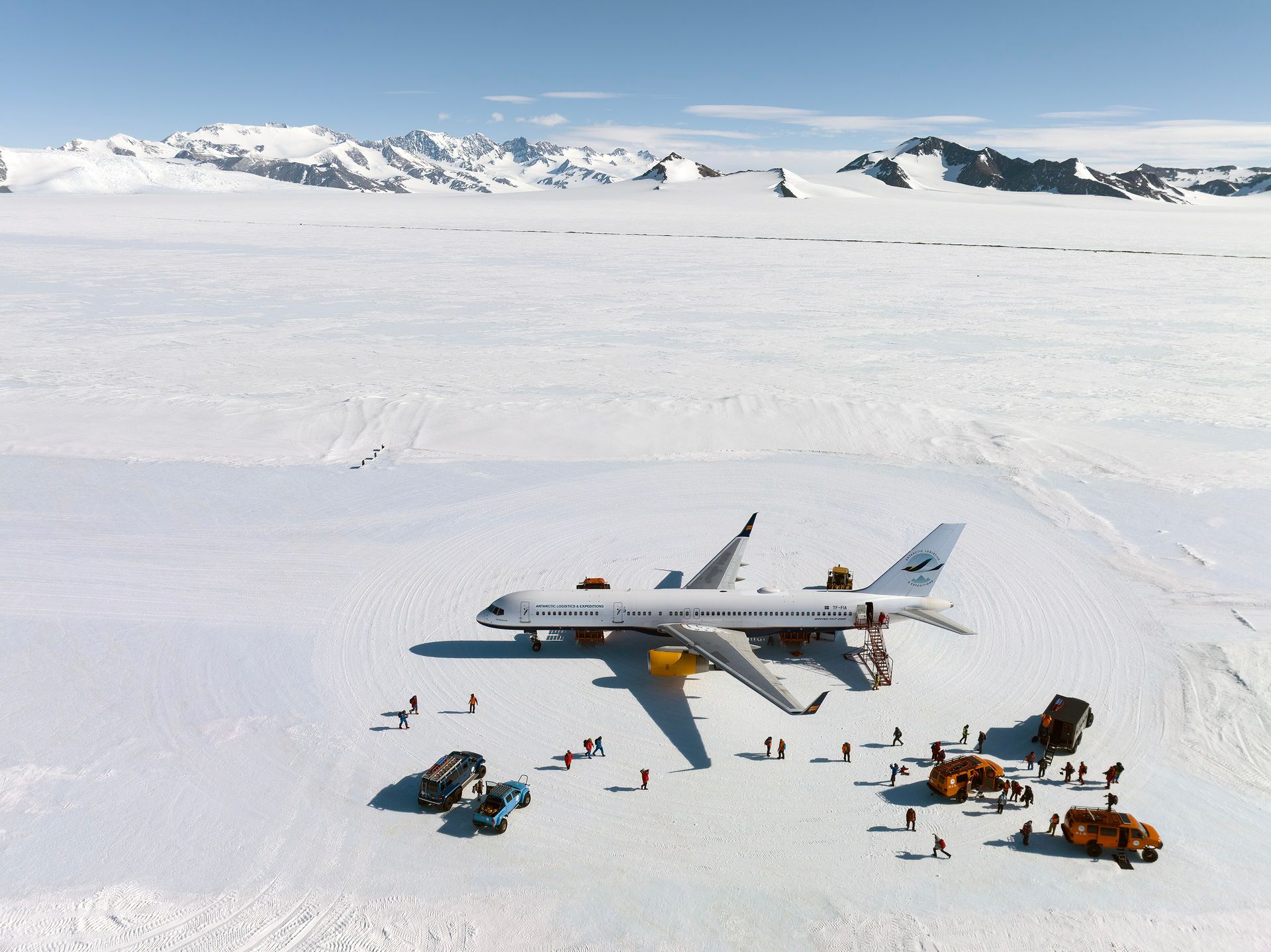 A Boeing 757 with ALE titles parked on the blue-ice runway at Union Glacier, with passengers and vehicles beside it