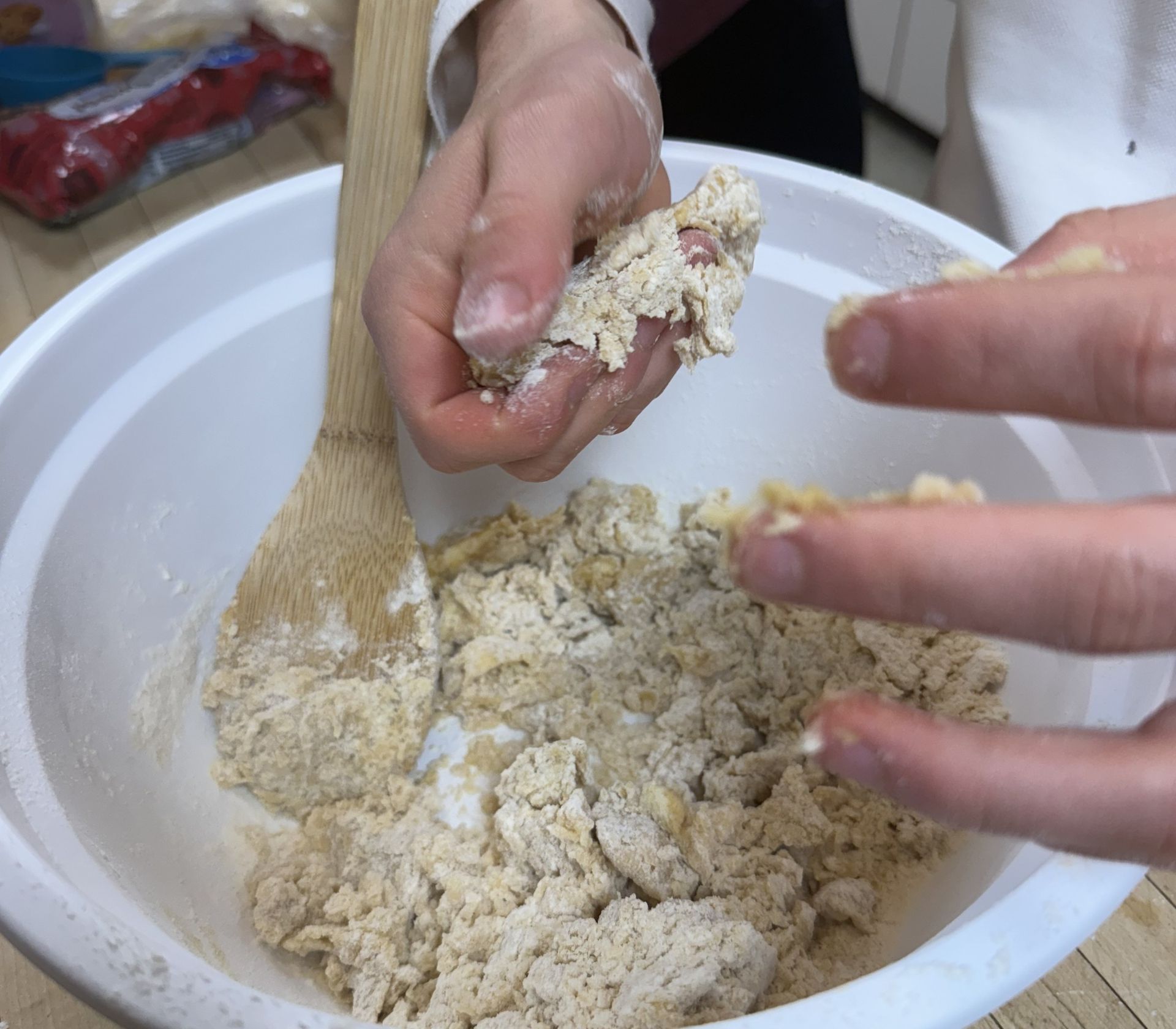 Students working dough together by hand in a big bowl
