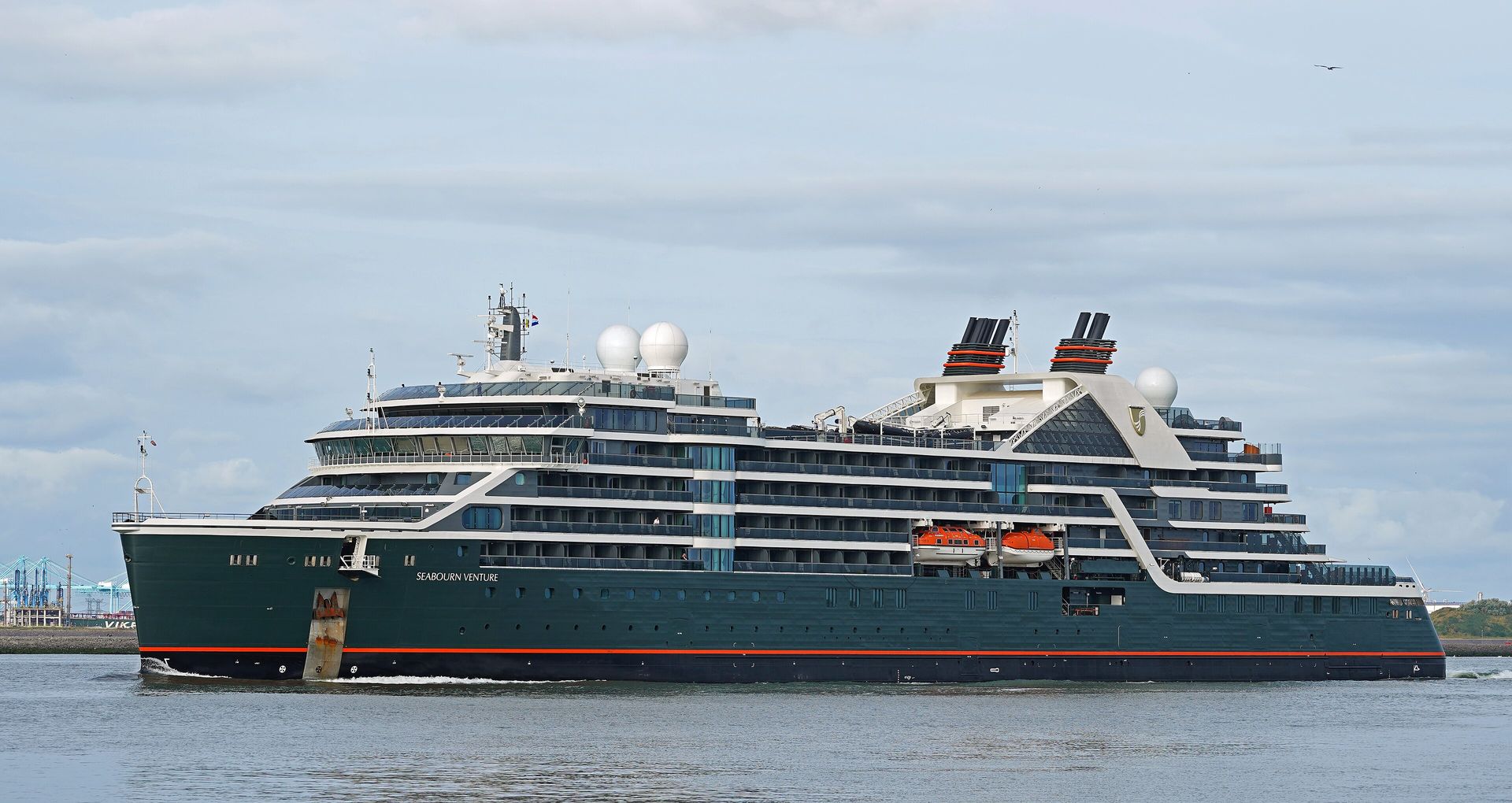 Seabourn Venture, a dark green expedition ship with white upper decks, sailing past Hoek van Holland in the Netherlands in July 2022