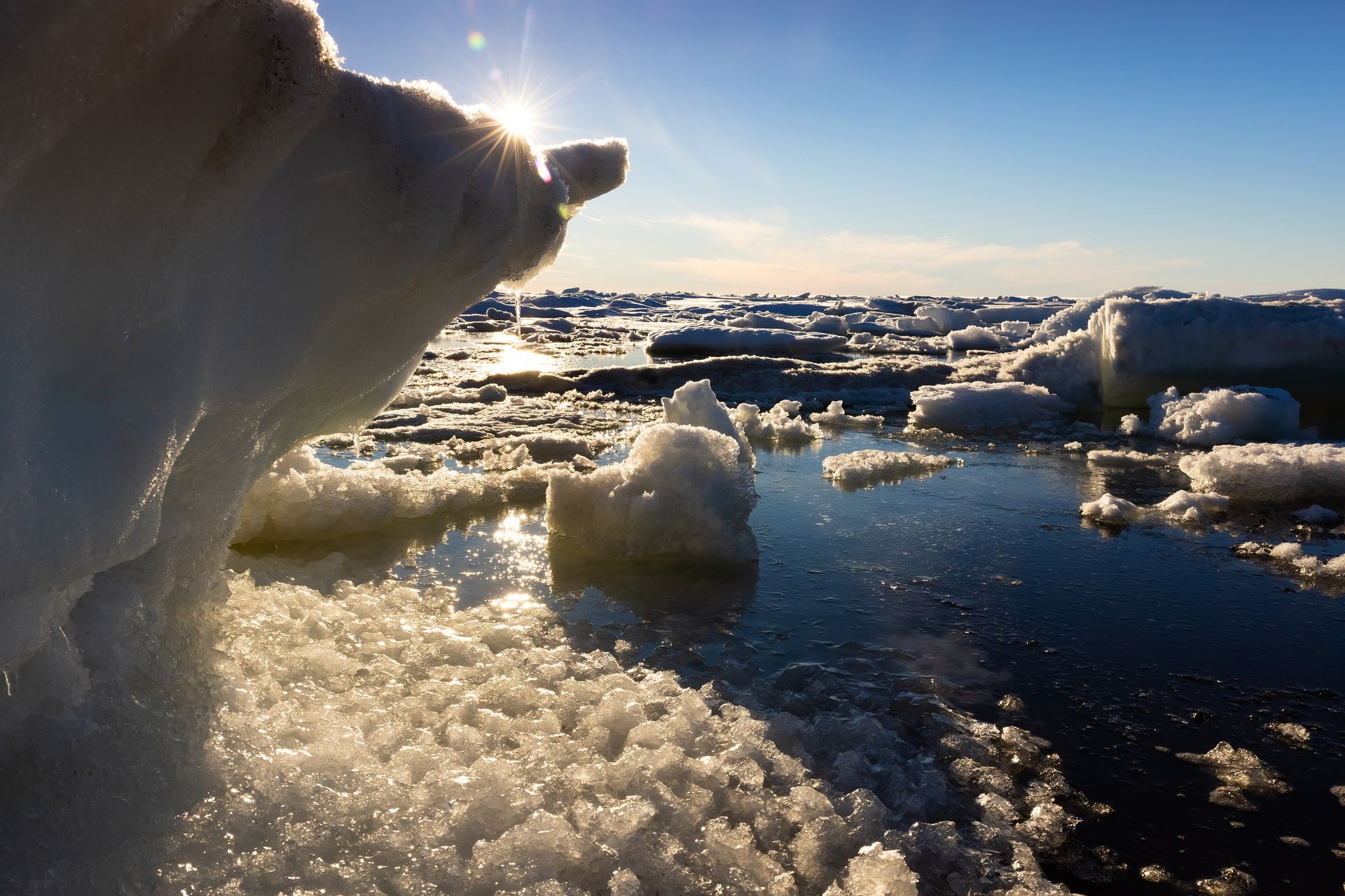 The midnight sun low over slabs of sea ice and open water on the Chukchi Sea off Utqiagvik, Alaska, in early July