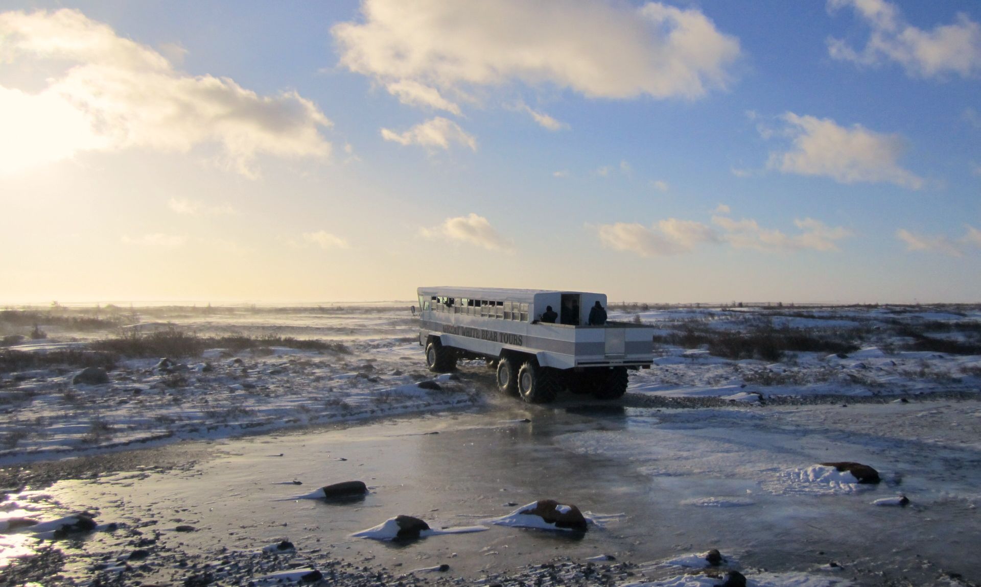 A Great White Bear Tours vehicle crosses frozen, snow-dusted tundra outside Churchill, Manitoba, in November
