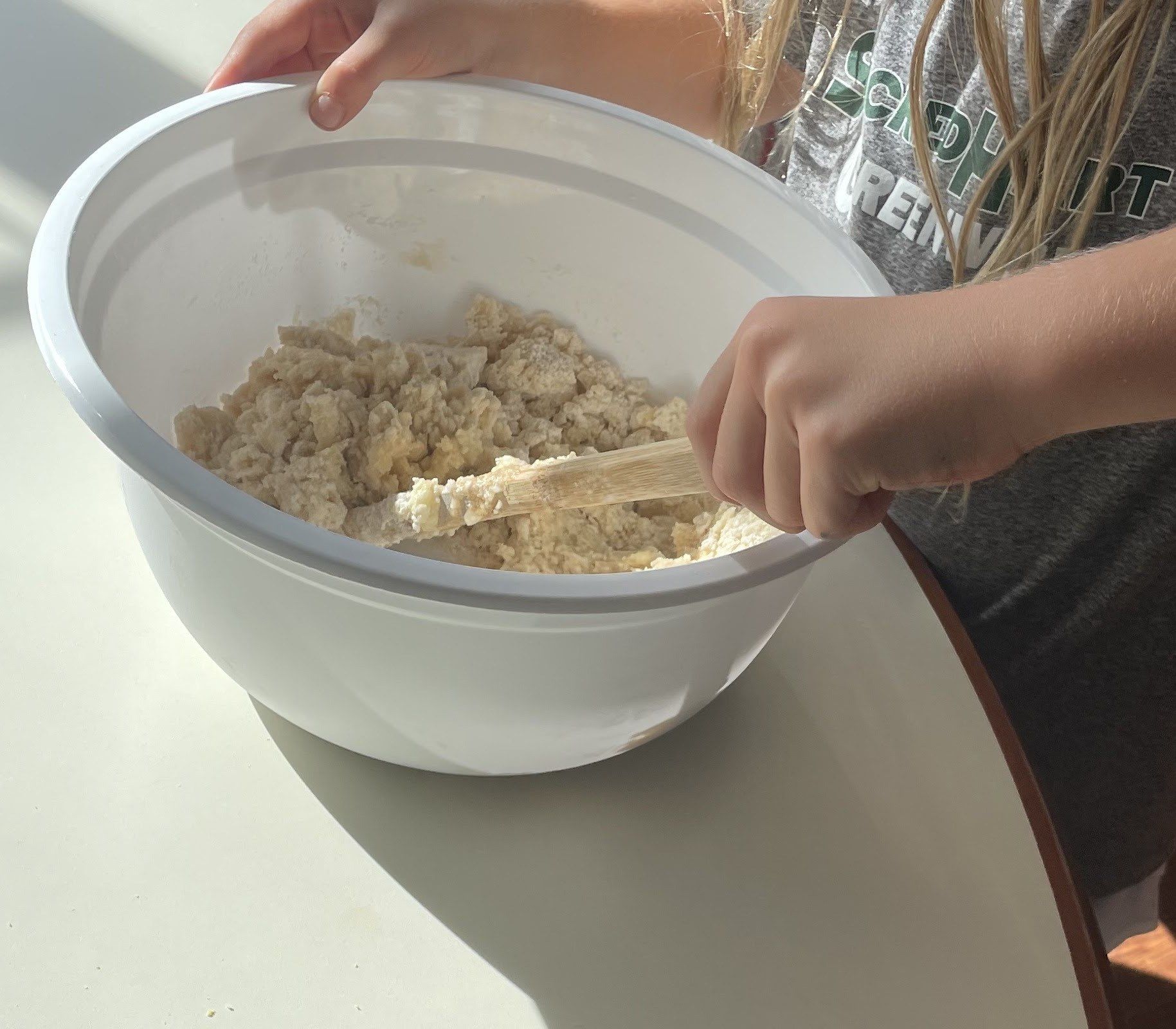 A student mixing dough in a sunlit after-school class