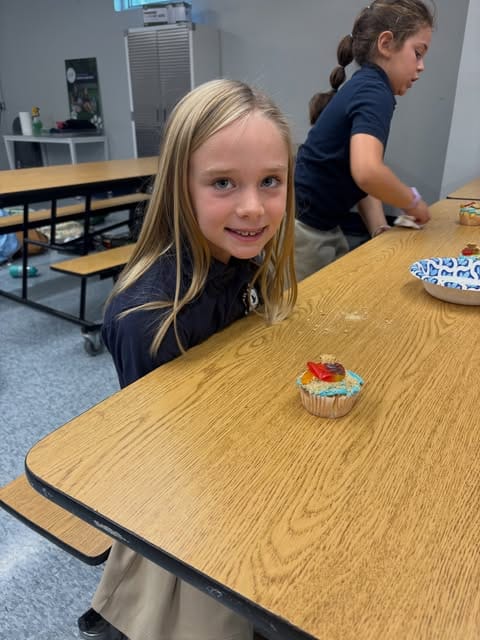 A girl proudly showing her decorated cupcake