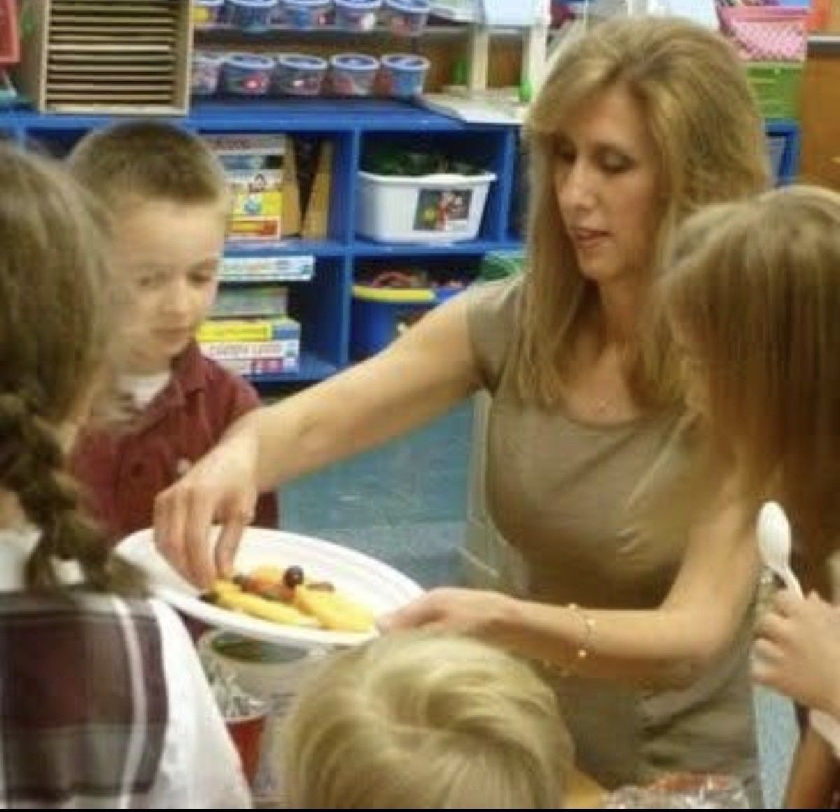 Cathy McCarthy serving a fruit snack to young children