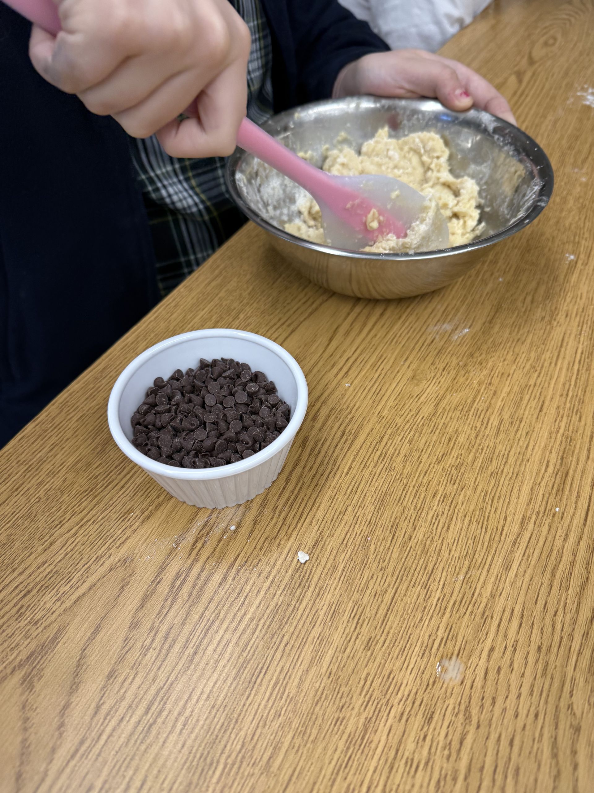 A child mixing cookie dough next to a dish of chocolate chips