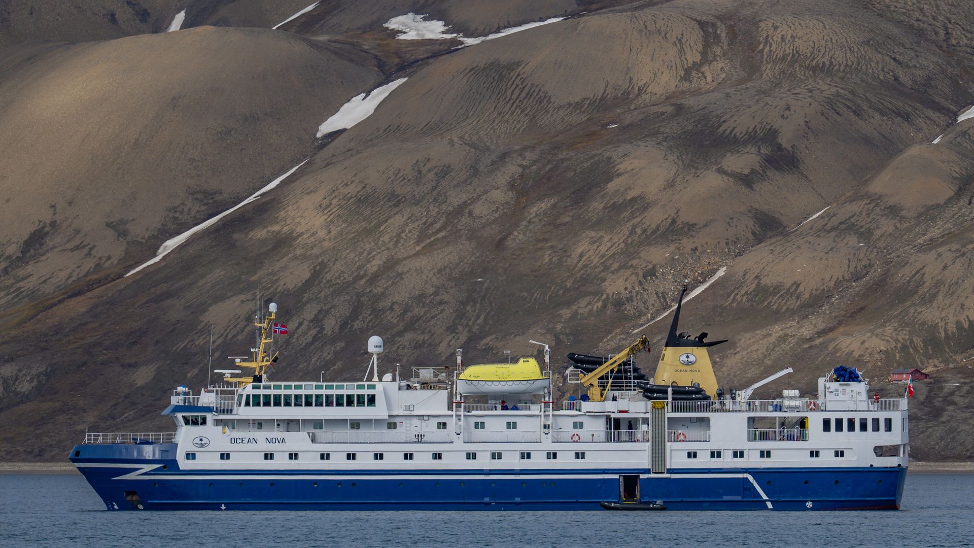 Expedition ship Ocean Nova, one of three ships Intrepid sells for Antarctica in 2026-27, below snowy hills in 2025