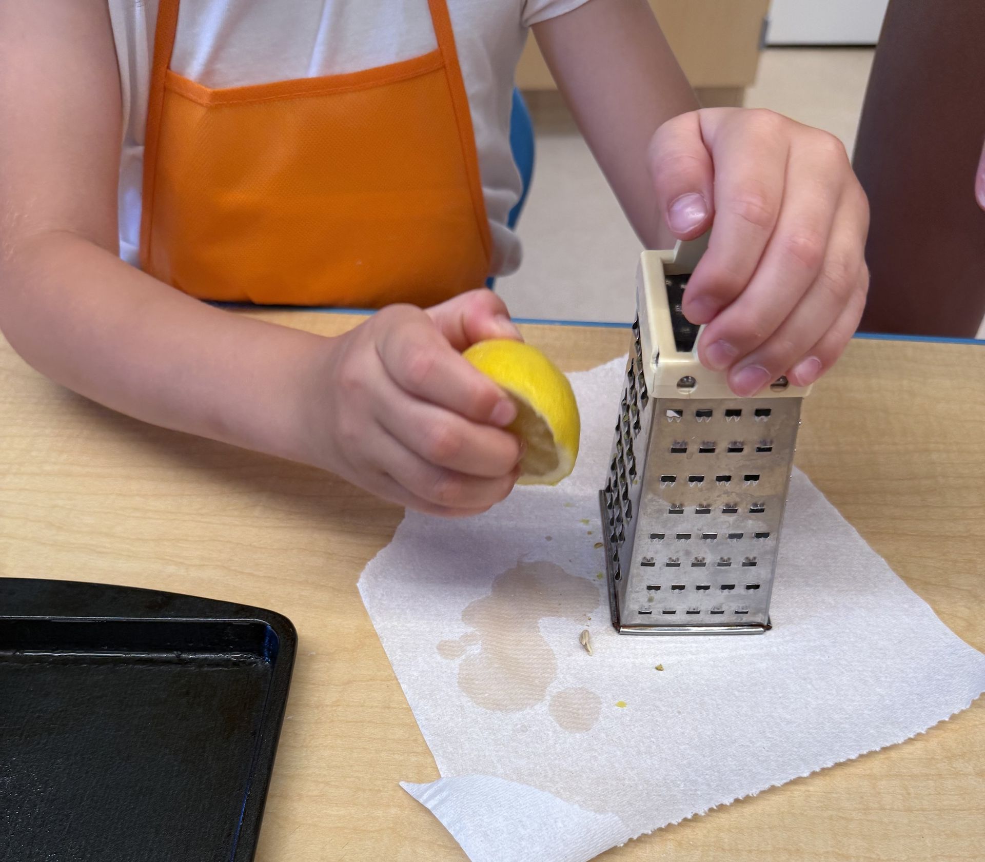 A summer camper zesting a lemon on a box grater