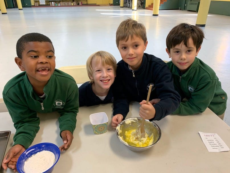 Four smiling boys around a bowl of batter