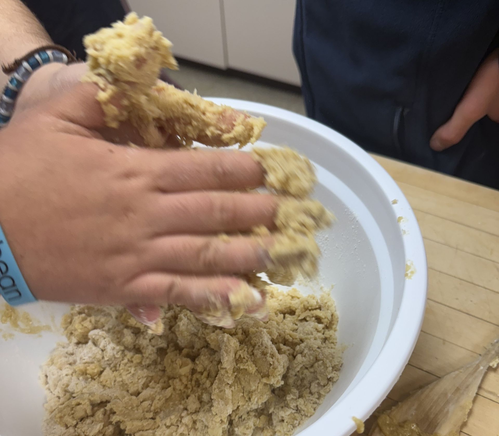 A student squeezing cookie dough together by hand