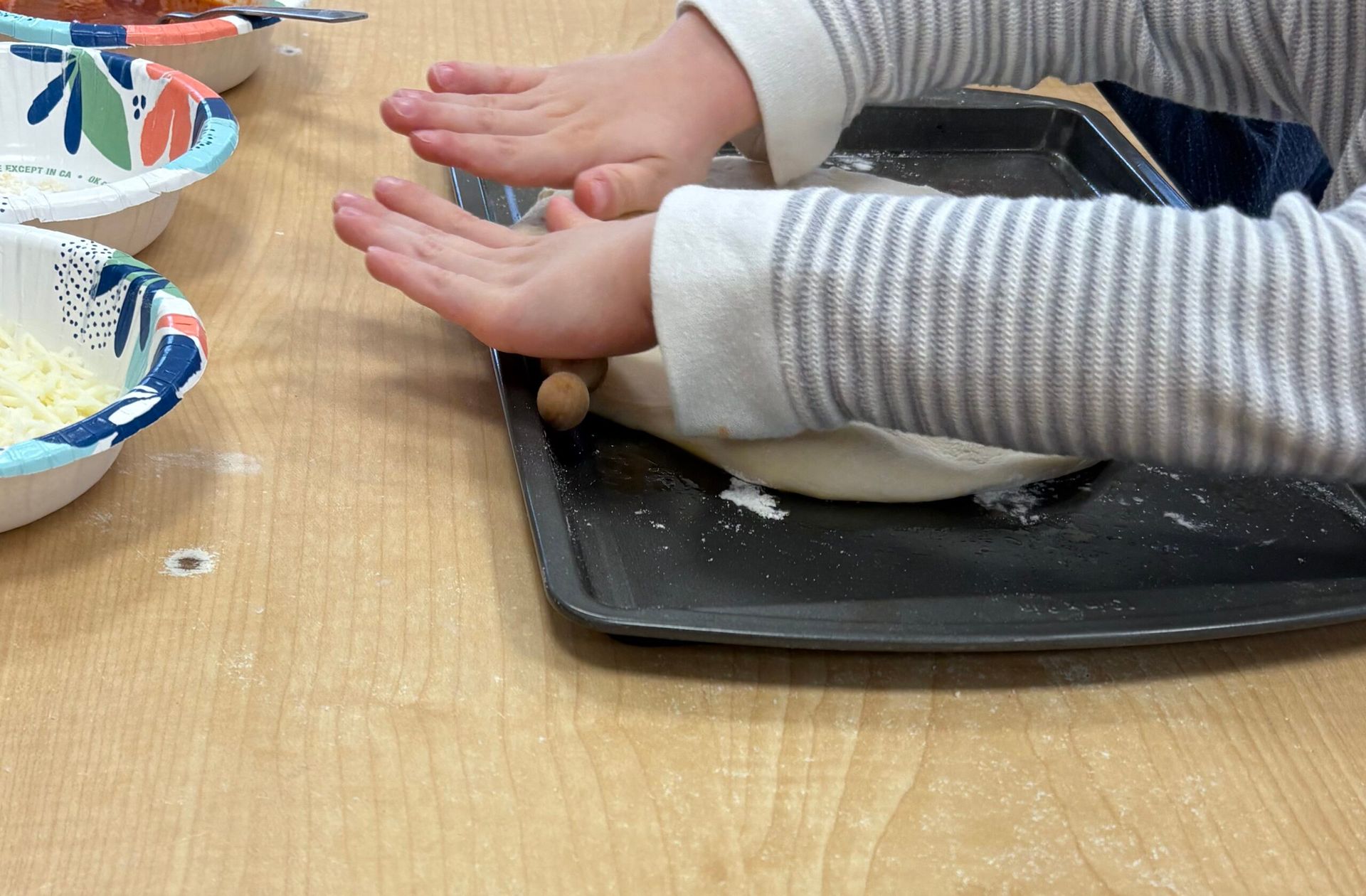 Small hands rolling dough on a baking tray