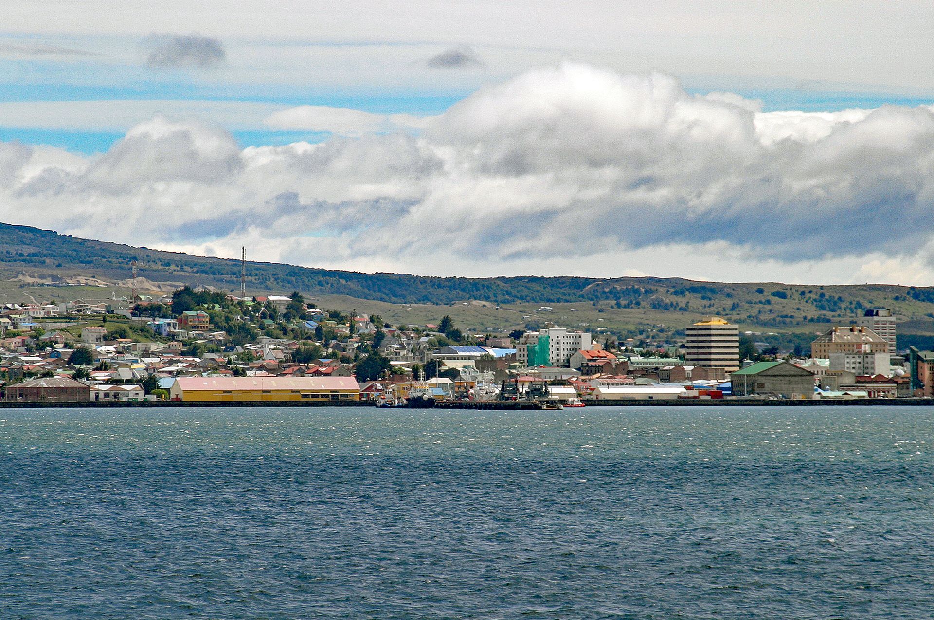 Punta Arenas seen from the Strait of Magellan, with the waterfront, low hills and clouds behind the city