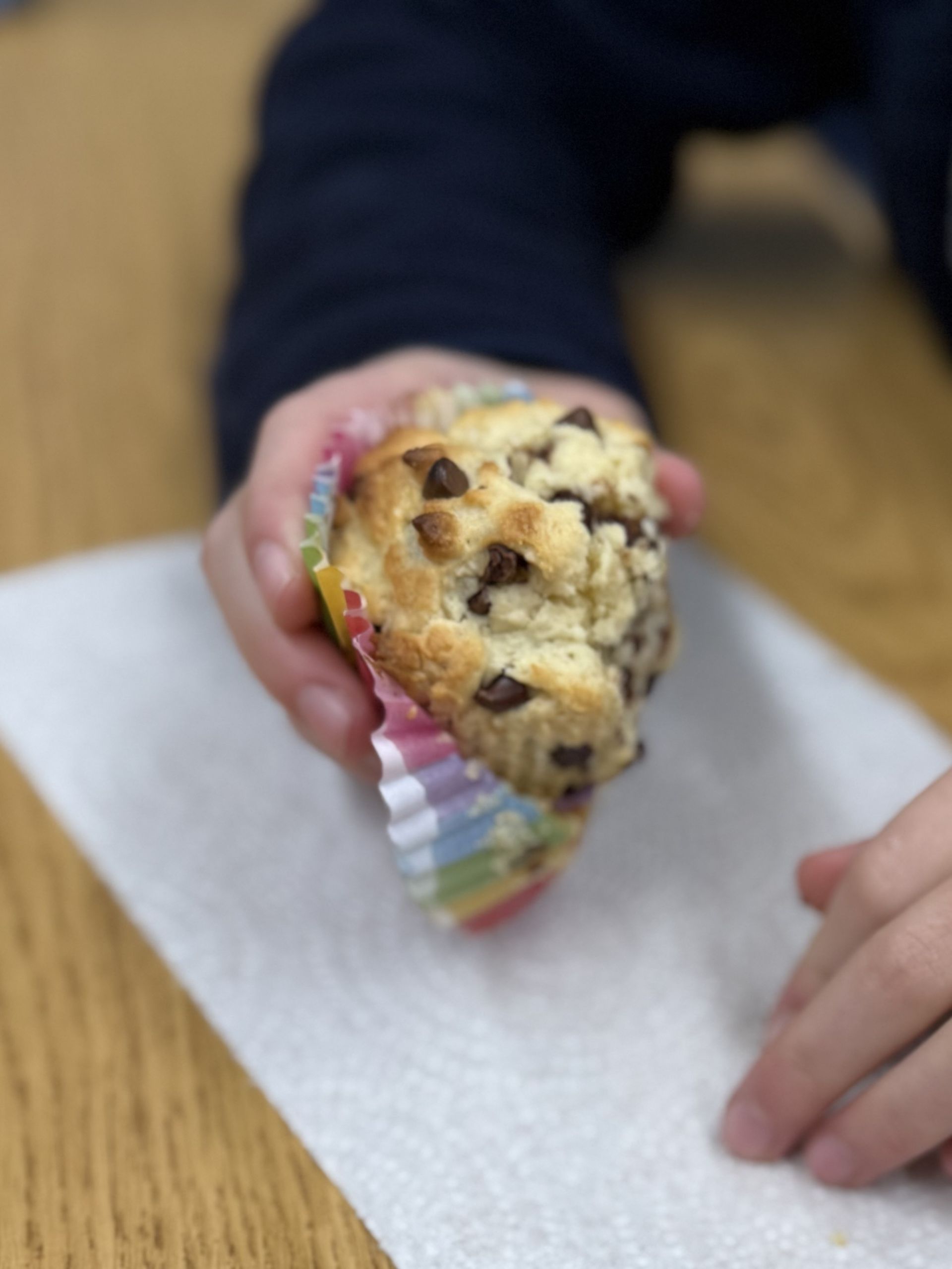 A child holding a fresh chocolate chip muffin