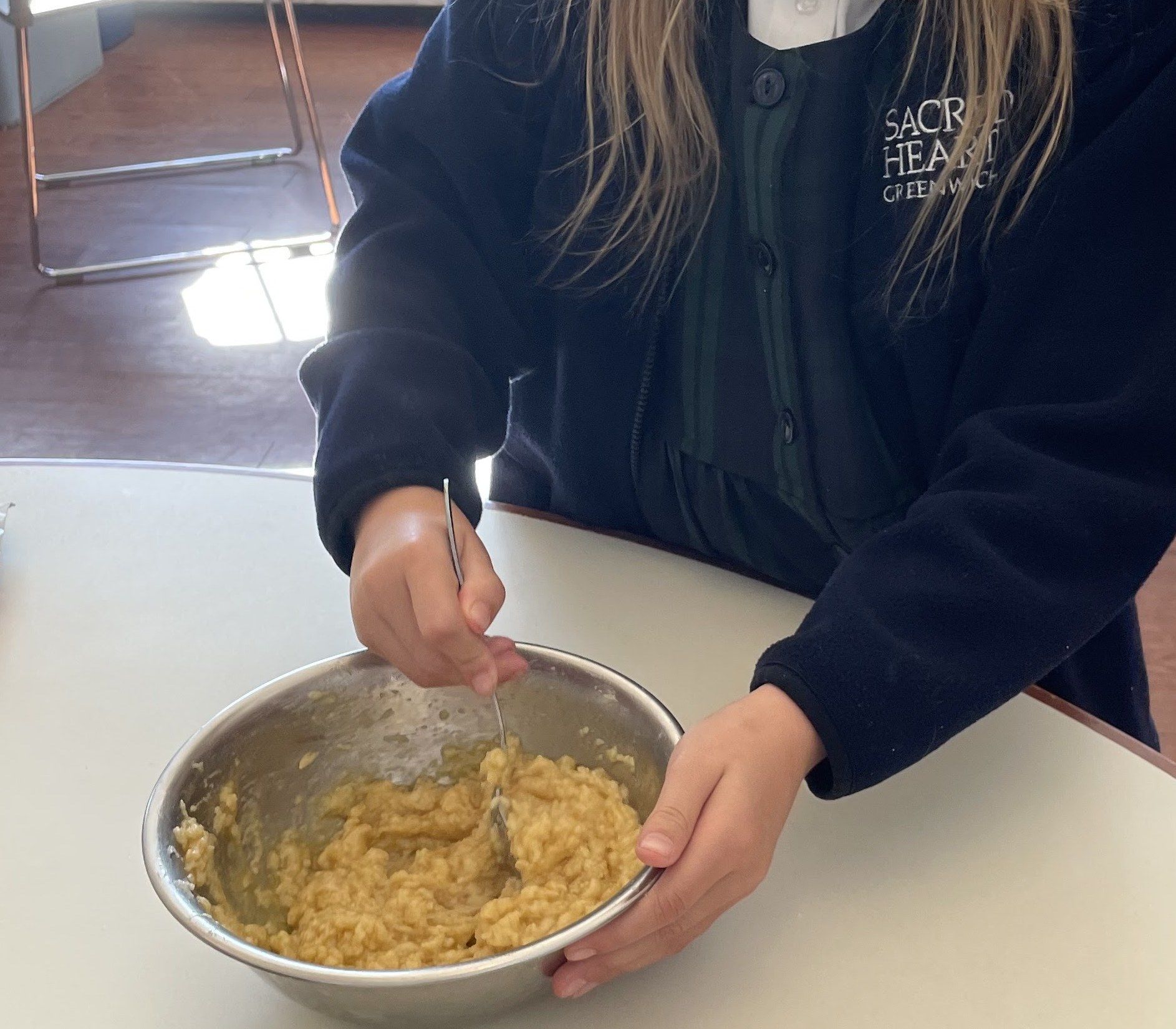 A student mixing batter in a steel bowl