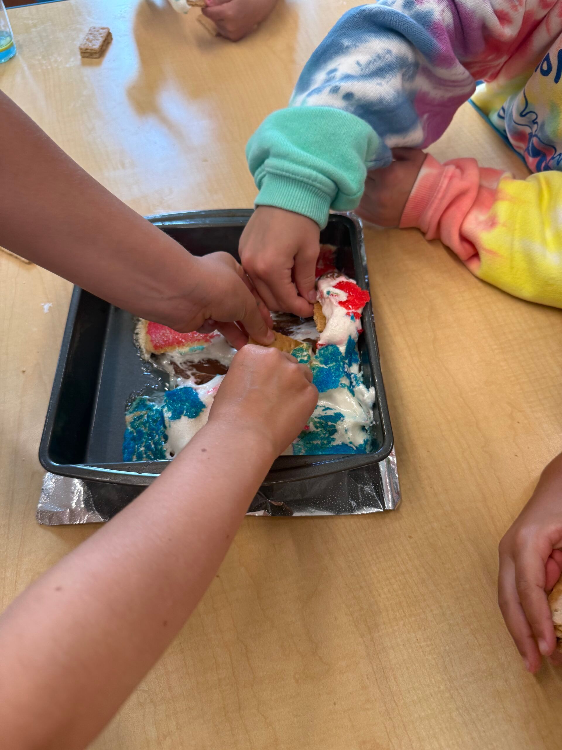 Children decorating treats on a baking tray