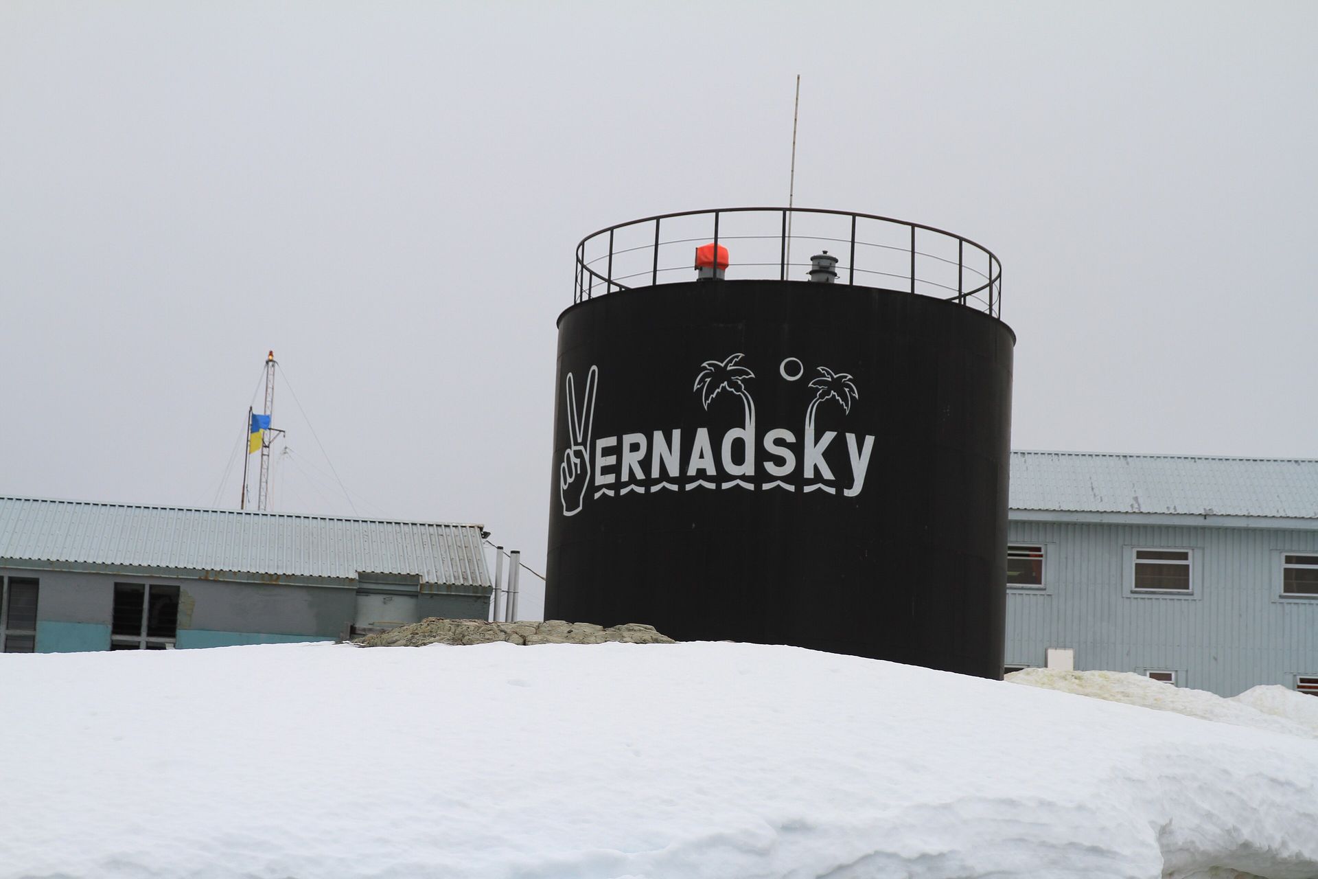 Deep snow in front of a tank and buildings at Ukraine's Vernadsky research station under a gray Antarctic sky