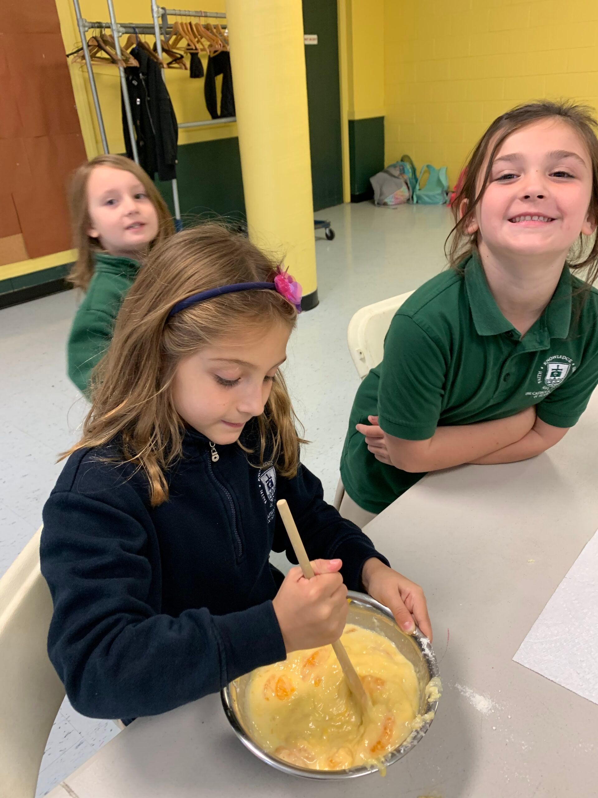 A girl stirring batter while her friends cheer her on