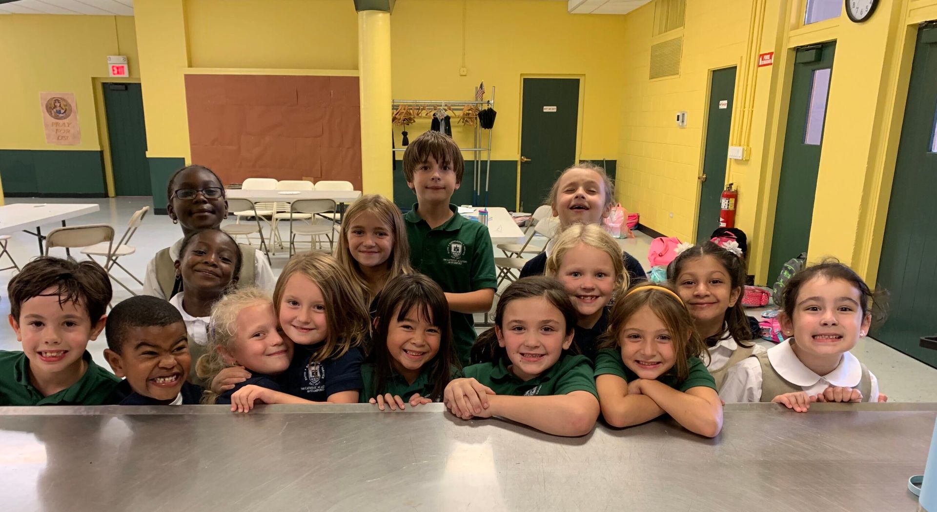 A full class of smiling students around a long table