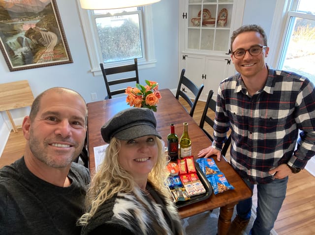 Michael and Kim sharing a laugh with a client over a closing gift of wine and treats