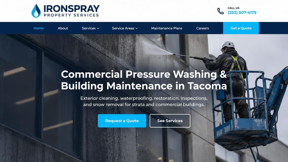 Pressure washing website design, commercial building washing from a lift: white header with a phone number and a navy menu bar, a worker on a lift pressure washing a concrete building, a centered white headline, a bright blue button