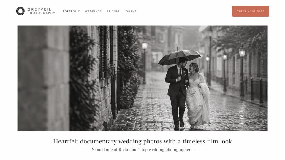 Wedding photographer website design, documentary wedding photographer on a rainy black and white street: white page, a terracotta button in the header, a wide black-and-white photo of a couple under an umbrella on a rainy cobbled street, a centered dark serif headline below
