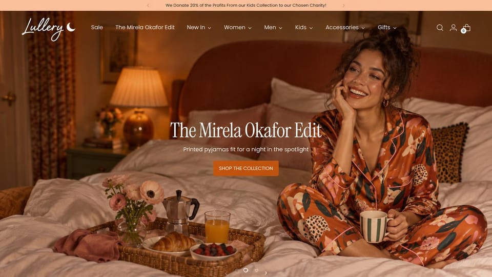 Fashion website design, printed pajamas with a guest edit in the menu: peach top bar, a lamp-lit bedroom with a smiling woman in printed satin pajamas on the bed beside a breakfast tray, a white condensed serif headline and an orange button