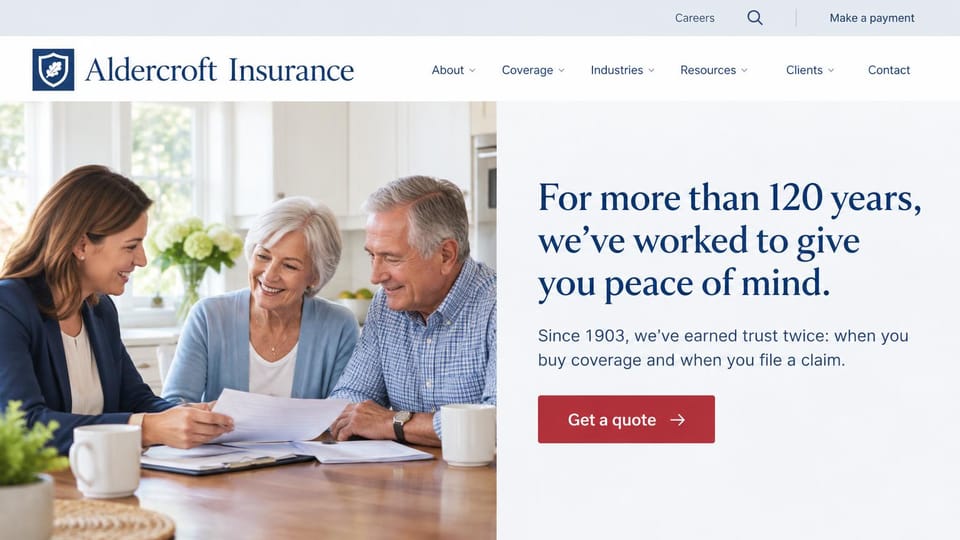 Insurance agency website design, established agency with a split hero: an advisor with an older couple at a kitchen table on the left, navy serif headline on pale gray on the right, red quote button