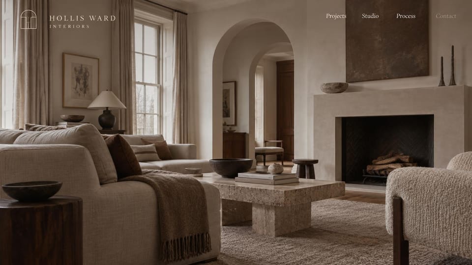 Interior design website design, portfolio that lets one room do the talking: a full-screen greige living room with arched doorways and a stone fireplace, a white serif logo and menu