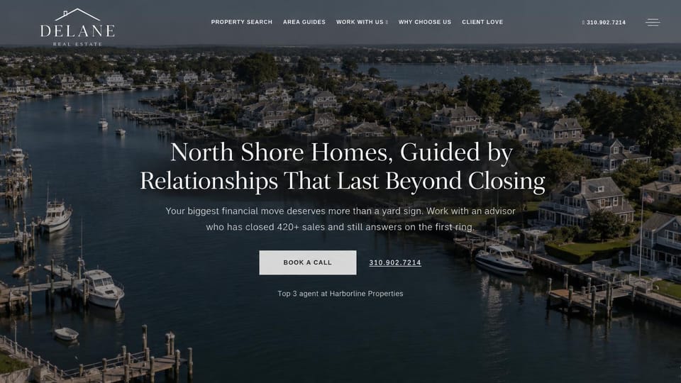 Real estate website design, harbor town agent at dusk: aerial harbor with boats at dusk, a centered white serif headline, a gray button and a phone link