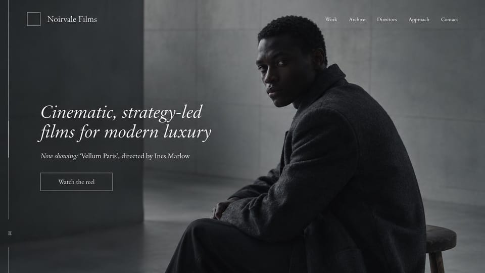 Videographer website design, luxury fashion films in black and white: black and white, a man in a dark coat seated on a stool against concrete, white italic serif headline, outlined reel button, a thin vertical line at left