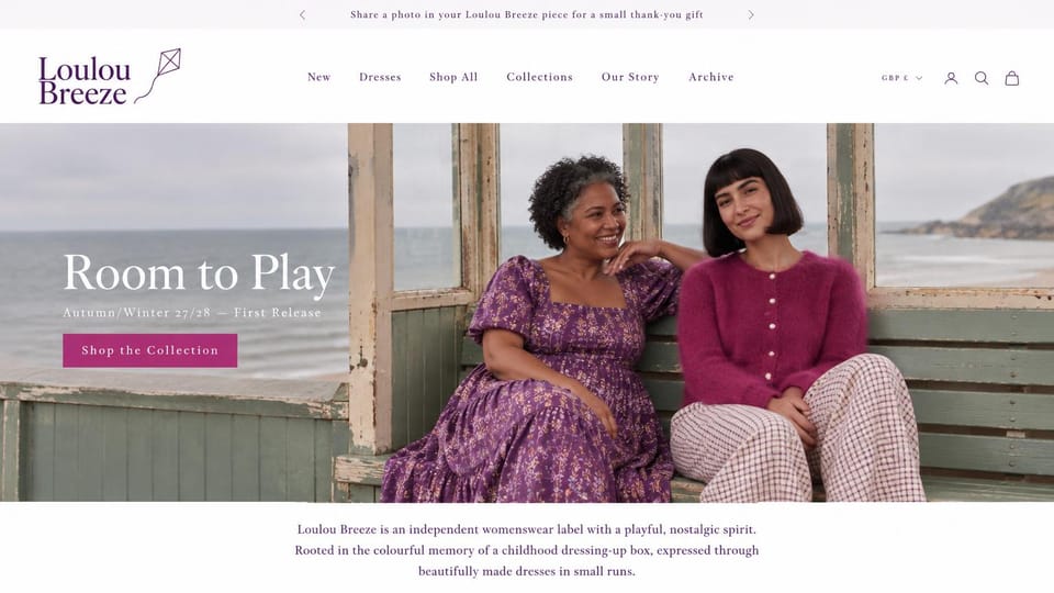 Fashion website design, playful dresses in a seaside shelter: white header with a plum kite logo, two smiling women in a purple floral dress and a magenta mohair cardigan in a weathered seaside shelter, a white serif headline, a magenta button and a centered plum paragraph below