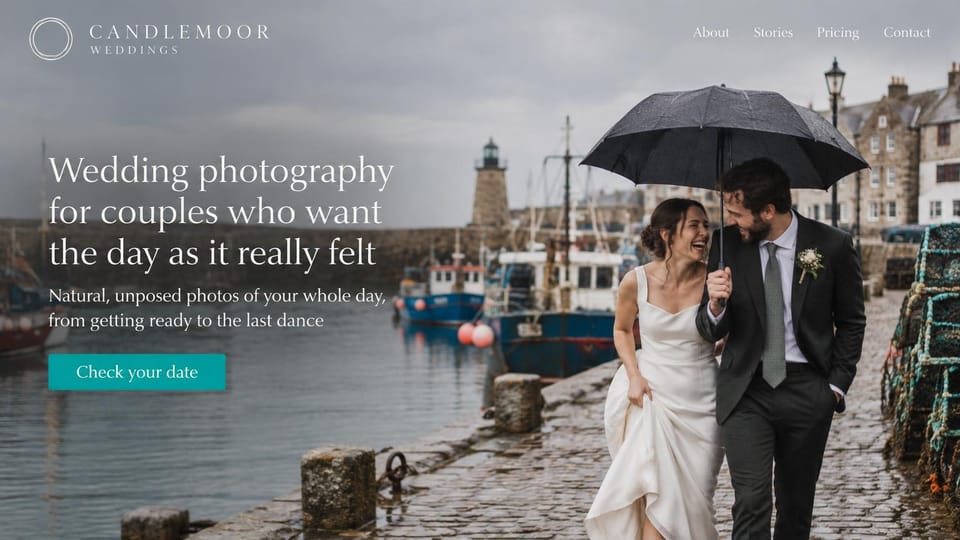 Wedding photographer website design, rainy-day wedding photographer at a harbor: grey harbor with fishing boats and a lighthouse, a couple laughing under a black umbrella on wet cobbles, a white serif headline and a teal button