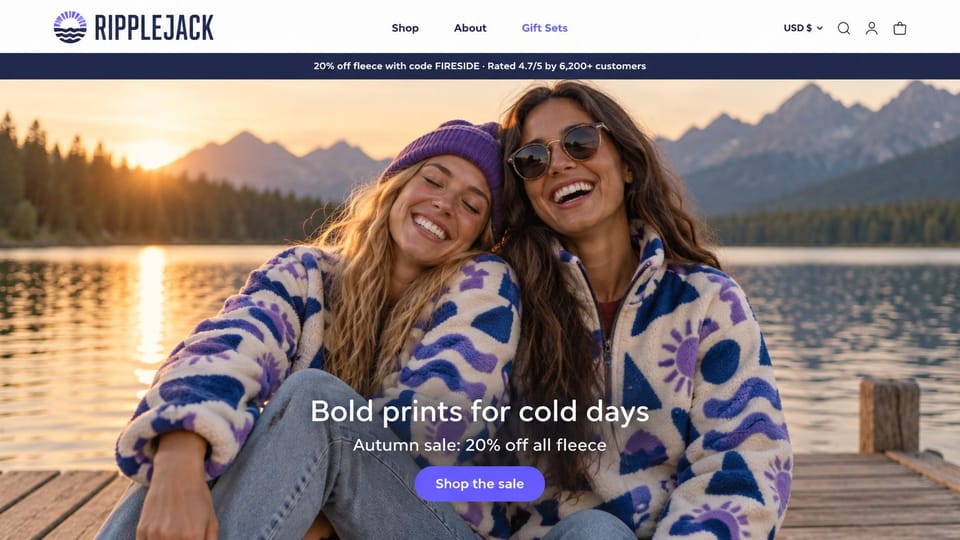 Fashion website design, printed fleece on a lake dock at sunset: two women laughing on a lake dock at sunset in cream fleece with a bold blue and purple print, a white headline and a purple button