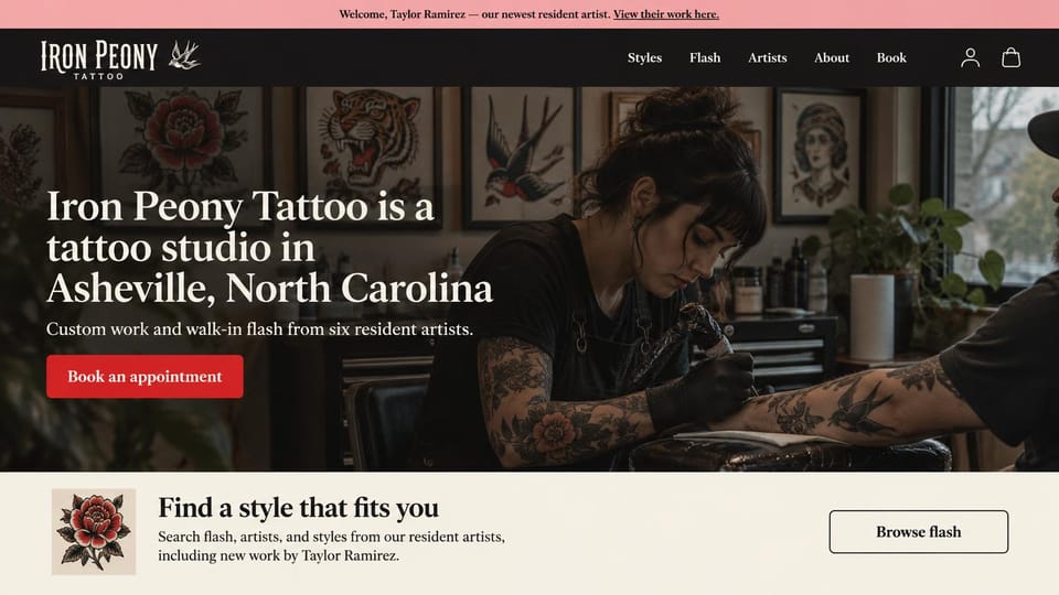 Tattoo website design, traditional shop with a flash wall and a style finder: pink announcement bar, a tattooer working in front of a wall of traditional flash, a white serif headline, a red button, a cream strip with a rose and a browse button