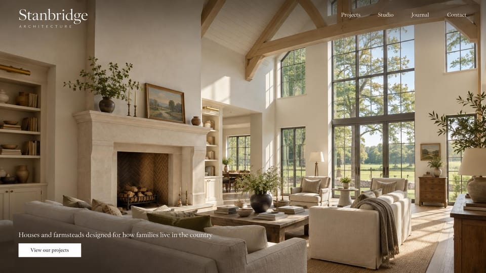 Architecture website design, country homes and farmhouses, warm and traditional: a sunlit farmhouse living room with a stone fireplace, timber beams and tall windows, a white serif wordmark, a short white line and button at lower left