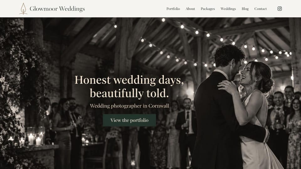 Wedding photographer website design, black and white wedding photographer with a dark green button: cream header with a flame logo, a full-screen black and white photo of a couple dancing in a beamed barn under string lights, a cream serif headline and a dark green button
