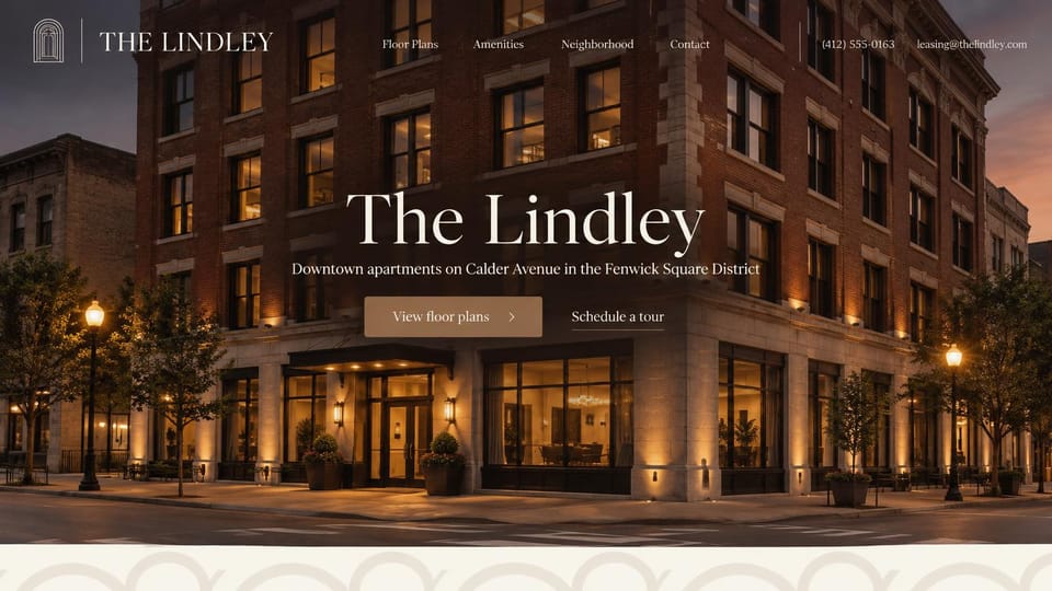 Apartment website design, historic downtown building at dusk: a brick and stone corner building at dusk with lit windows and street lamps, a large centered cream serif name, a tan floor plans button and a tour link