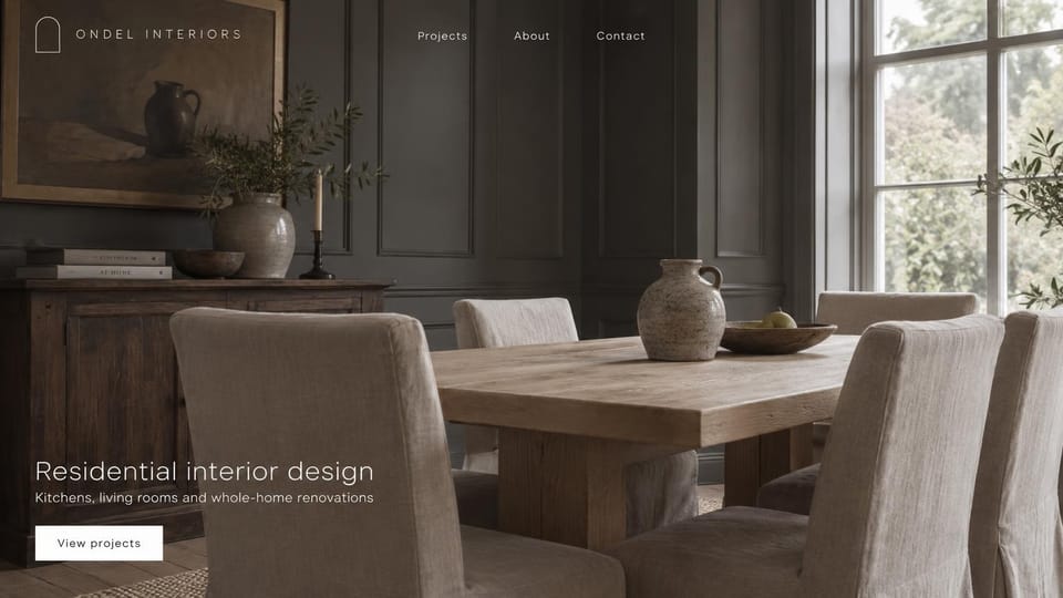 Interior design website design, kitchens and living rooms against dark paneled walls: a dim charcoal-paneled dining room with an oak table and linen chairs, a thin white sans-serif headline and logo, and a white button
