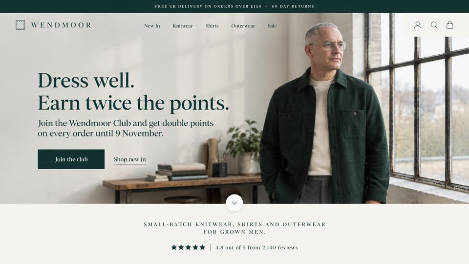 Fashion website design, menswear for grown men with a points club headline: dark green top bar, a spaced serif logo, a gray-haired man in glasses and a dark green wool overshirt by a tall factory window, a dark green serif headline and button, a star rating strip below