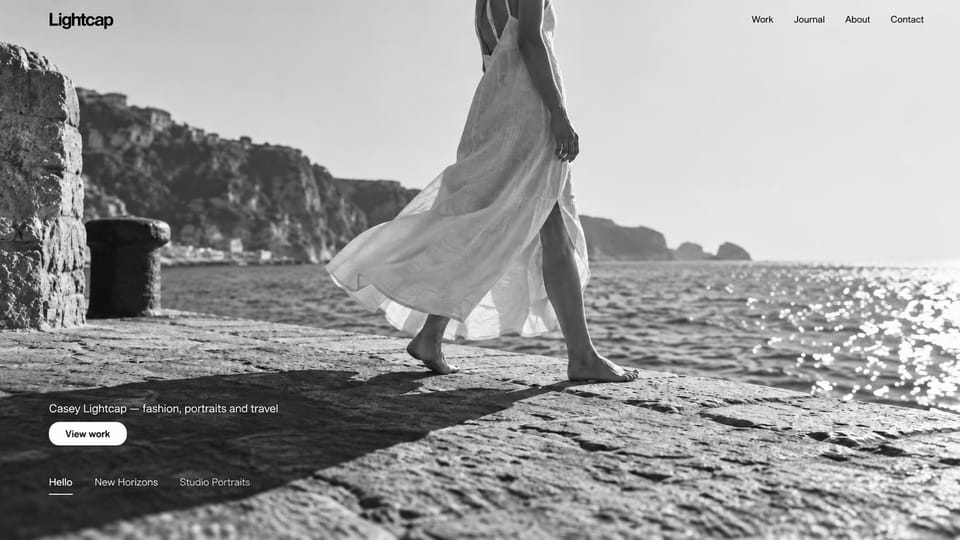 Photography website design, fashion and travel in black and white: a black and white photo of a woman in a white dress on a seaside path, small text and a white button at lower left