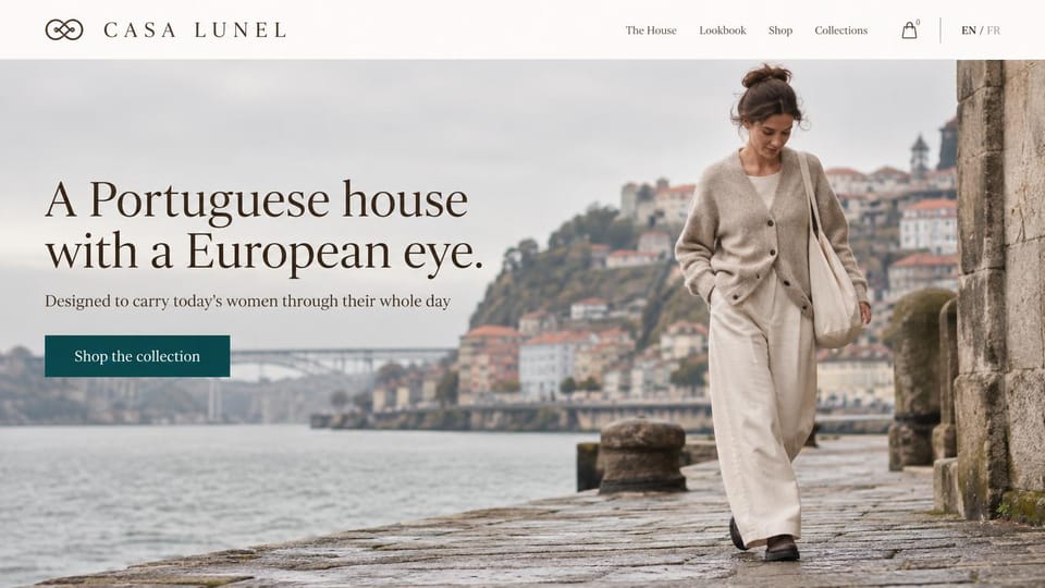 Fashion website design, womenswear on a riverside quay with a language switch: a woman in an oatmeal cardigan and cream trousers with a canvas tote on a stone riverside quay, red roofs and an iron bridge behind, a serif headline and a teal button