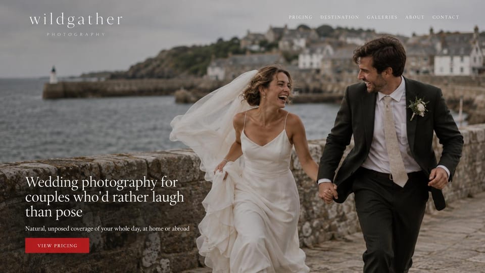 Wedding photographer website design, wedding photographer at home and abroad with a red pricing button: full-width photo of a laughing couple running along a stone harbor wall with a lighthouse and town behind, a light serif logo, a white serif headline and a red pricing button