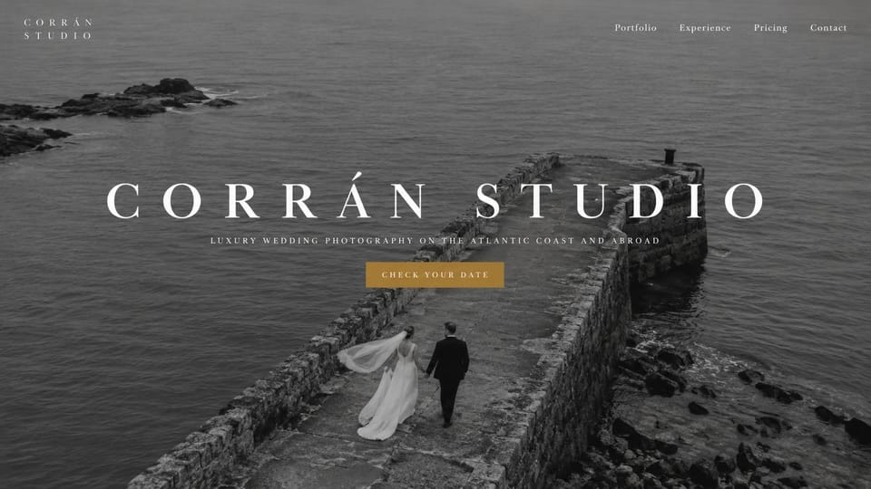 Wedding photographer website design, luxury coastal wedding photography in black and white: black-and-white aerial photo of a couple walking a stone pier into the sea, a wide spaced white serif name, small capitals and a gold button