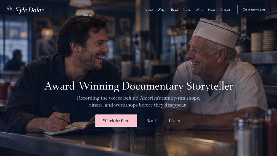 Videographer website design, documentary storyteller with films, writing and audio: dark diner photo of a smiling filmmaker with a notebook and an older cook in a paper hat, centered white serif headline, pink button