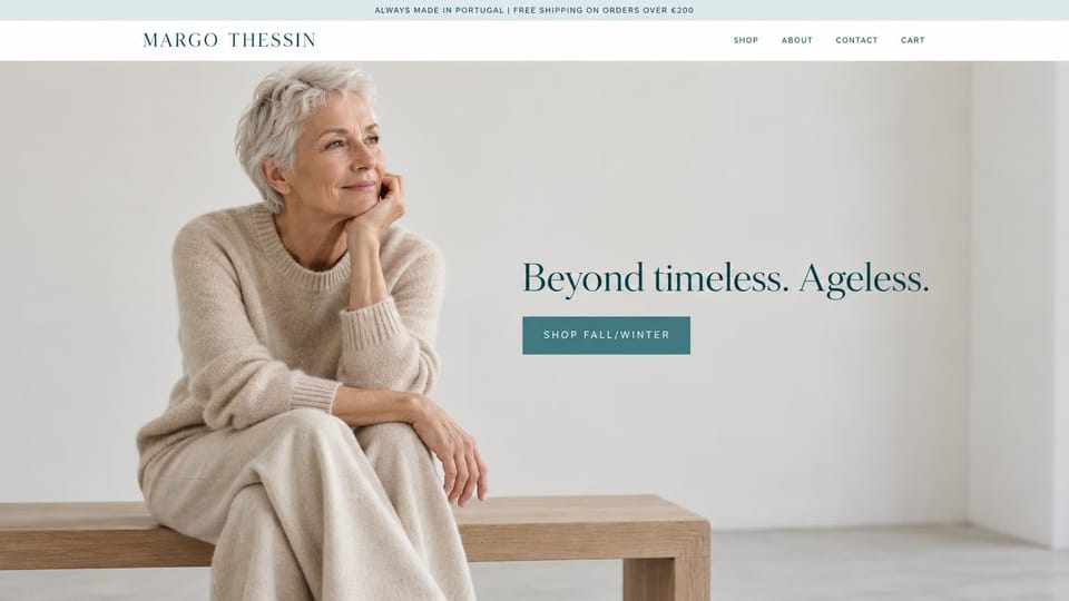 Fashion website design, ageless knitwear on a calm white page: white header with a spaced serif name, a pale studio with a smiling silver-haired woman in an oatmeal knit sweater and skirt on an oak bench, a teal serif headline and a teal button
