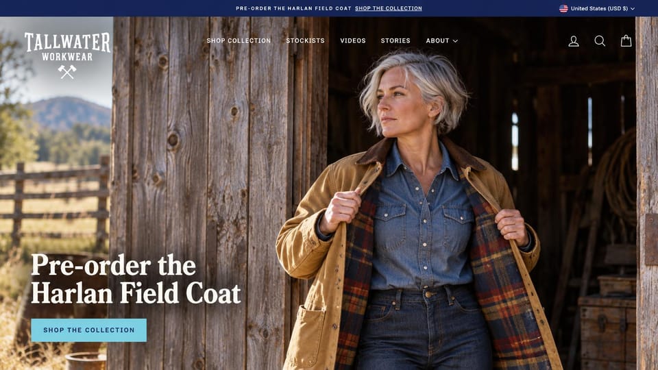 Fashion website design, women's field coats in a weathered barn: navy top bar, a white condensed logo with crossed axes, a silver-haired woman opening a waxed tan coat with a plaid lining in a barn doorway, a white serif headline and a light blue button