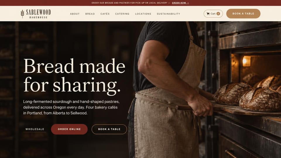 Bakery website design, sourdough bakery with cafes and wholesale: dark photo of a baker pulling loaves from a deck oven, a large white serif headline, a deep red order button and a red top bar
