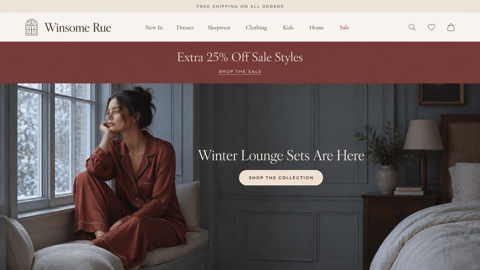 Fashion website design, boutique lounge sets under a burgundy sale band: cream header, a burgundy sale band, a woman in a rust satin lounge set by a snowy window in a blue-gray bedroom, a centered white serif headline and a pale pill button
