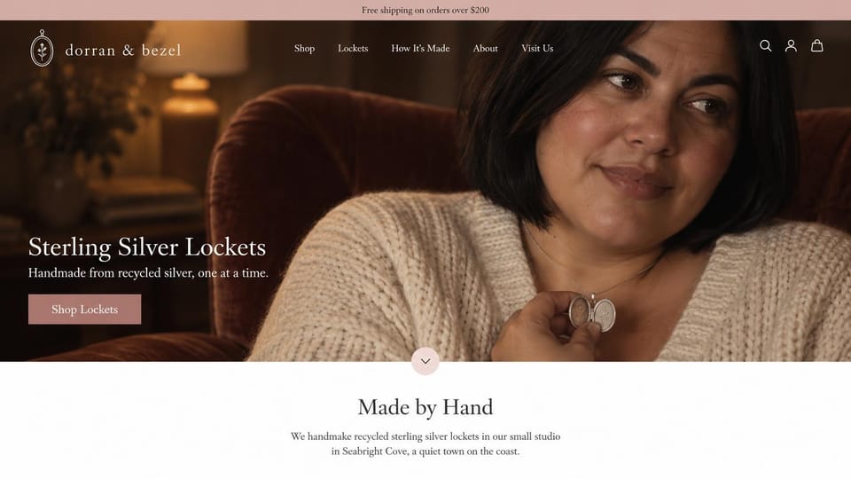 Jewelry website design, silver lockets in a cozy living room: dusty rose top bar, dark warm photo of a woman in a cream cardigan holding open a silver locket, cream serif wordmark with a locket mark, rose shop button, white section with a centered serif heading