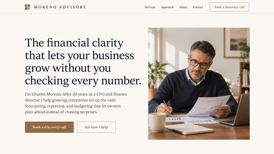 Consulting website design, fractional CFO with a portrait at the desk: warm cream page, large navy serif headline, brown discovery call button, a consultant in glasses reviewing financial reports at a desk